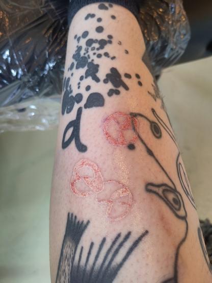 Bloody white ink abstract tattoo on a lower leg