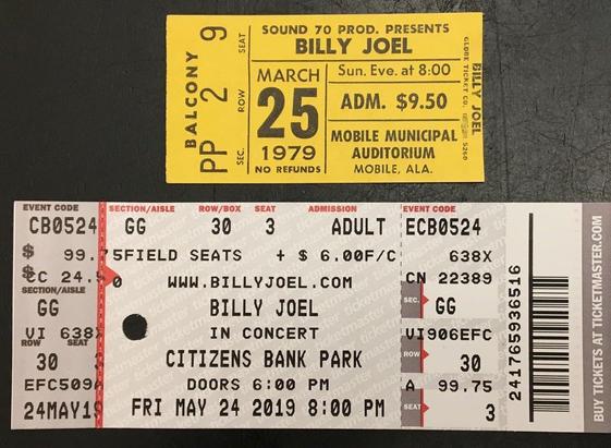 Two rectangular ticket stubs. One smaller, yellow in color, Billy Joel 1979. One larger, primarily white and trimmed in gray, black and orange, Billy Joel 2019.