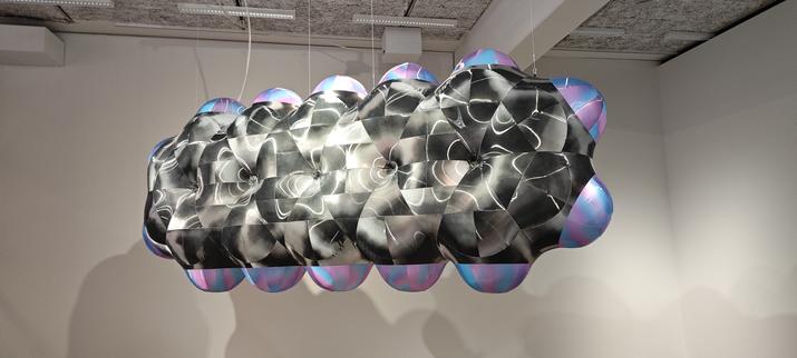 Ein schwebendes, schillerndes Objekt erinnert entfernt an ein Bündel von Helium Ballons, tatsächlich hat es die Form eines Pentacenes, der Verbindung eines Ölderivats, dass sich in fast allen Alltagsgegenständen wiederfindet.