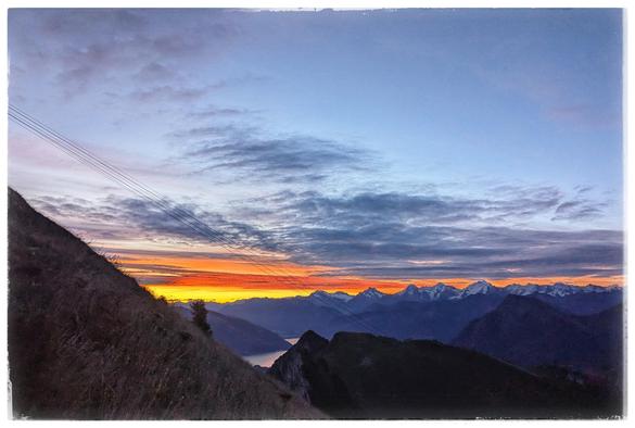 Image taken along a mountain side into a valley. A small patch of a lake, morning sun.