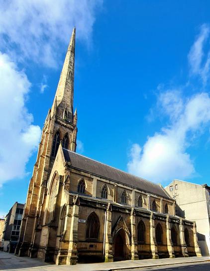An 1850s blonde sandstone Gothic style church.