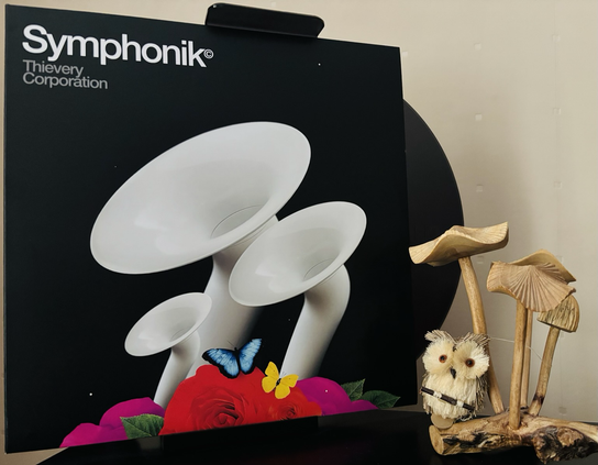 A black background with three various sized white horn looking objects popping up over a small bed of red and pink flowers that have a blue and yellow butterfly parked on them.