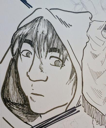 A young boy in a hooded cloak side-eyes the viewer. Another view of him from behind reveals the cloak is fringed and knee-length.
