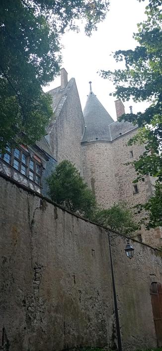 Vue sur une tour du château et une sorte de verrière en bois. Devant, un lampadaire