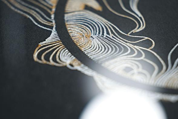 Macro closeup of a flowing design with lines radiating away from a circle in organic forms. Printed with a pen plotter on dark cardboard in two rounds, first silver and then gold on top, with me lifting the pen away manually to get areas without gold.
Zoomed in like this it almost looks like lace or stitches!