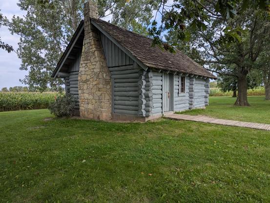 Exterior of a small grey log cabin house