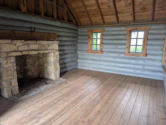 Interior of the same cabin. There is a large stone fireplace along the left side