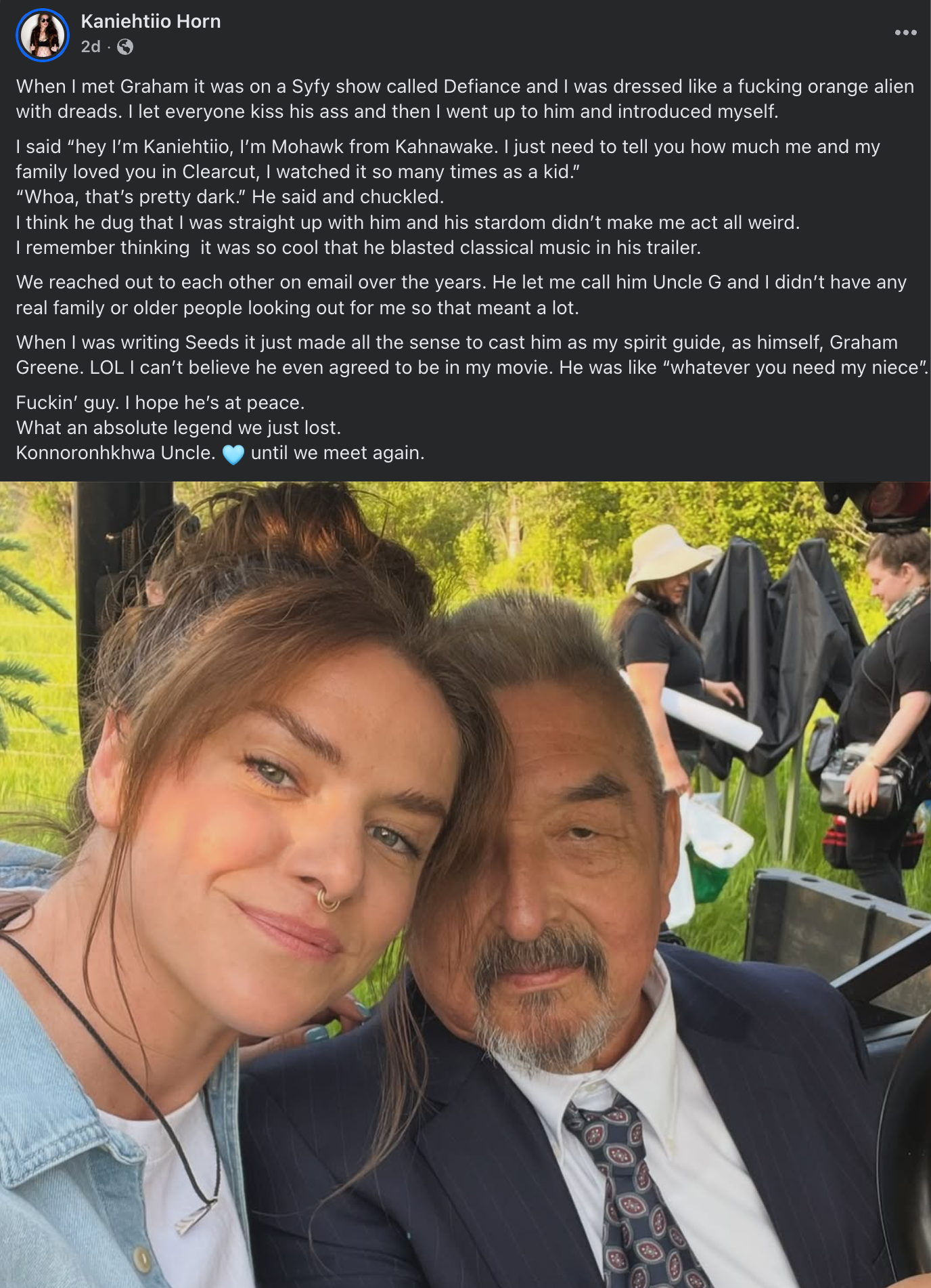 Facebook post by Kaniehtiio Horn including a photo of her and Graham Greene on the set of her film "Seeds" ••• When I met Graham it was on a Syfy show called Defiance and I was dressed like a fucking orange alien with dreads. I let everyone kiss his ass and then I went up to him and introduced myself. I said "hey I'm Kaniehtiio, I'm Mohawk from Kahnawake. I just need to tell you how much me and my family loved you in Clearcut, I watched it so many times as a kid." "Whoa, that's pretty dark." He said and chuckled. I think he dug that I was straight up with him and his stardom didn't make me act all weird. I remember thinking it was so cool that he blasted classical music in his trailer. We reached out to each other on email over the years. He let me call him Uncle G and I didn't have any real family or older people looking out for me so that meant a lot. When I was writing Seeds it just made all the sense to cast him as my spirit guide, as himself, Graham Greene. LOL I can't believe he even agreed to be in my movie. He was like "whatever you need my niece". Fuckin' guy. I hope he's at peace. What an absolute legend we just lost. Konnoronhkhwa Uncle. Until we meet again.