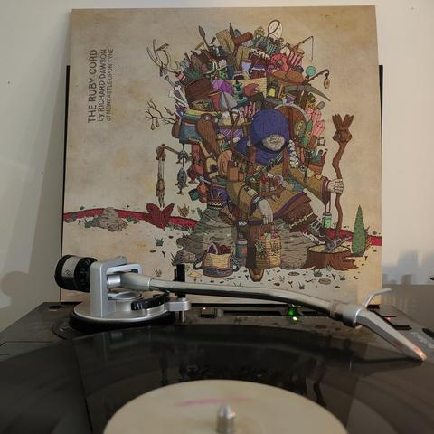 LP sleeve of Richard Dawson's The Ruby Cord propped up behind a turntable which is playing the album.