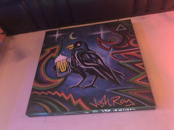 A funky abstract painting by Josh Roy of a crow holding a mug of beer