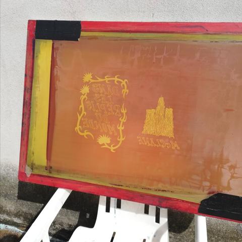 Écran de sérigraphie insolé en train de sécher posé sur une chaise en plastique.