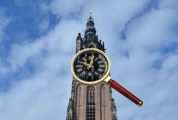 De Lieve Vrouwetoren in Amersfoort. Een vergrootglas zoomt in op de klok.