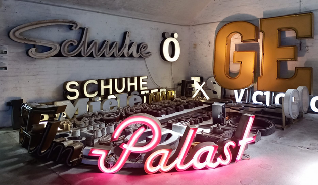 An der Wand 2 verschiedene Schriftzüge SCHUHE, auf dem Boden viele 3D-Buchstaben, im Vordergrund PALAST
