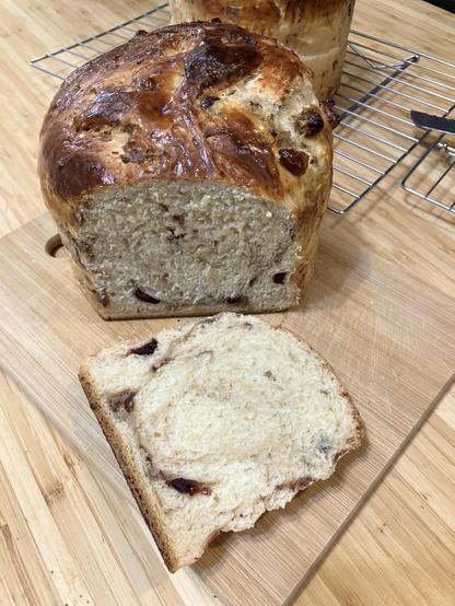 Two large loaves of panettone, one sliced on the cutting board.