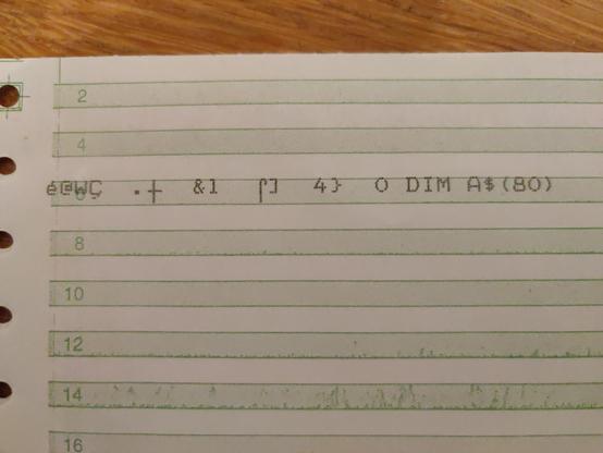 A close up if a line of garbage printed on green bar paper.

Most of the characters printed are not even in the ATASCII character set. At the end of the line is some valid text "0 DIM A$(80)"