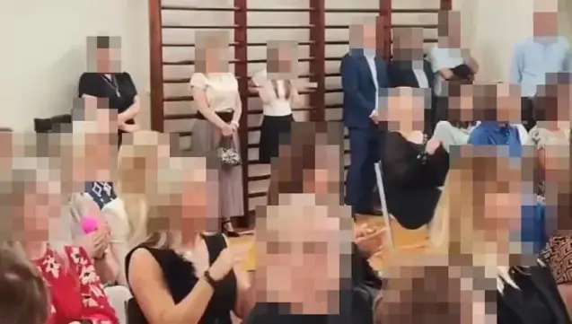 Grupa osób na szkolnej sali gimnastycznej - każda postać ma rozmazane rysy twarzy, w rezultacie jedynymi nierozpikselowanymi elementami są drabinki i ręce