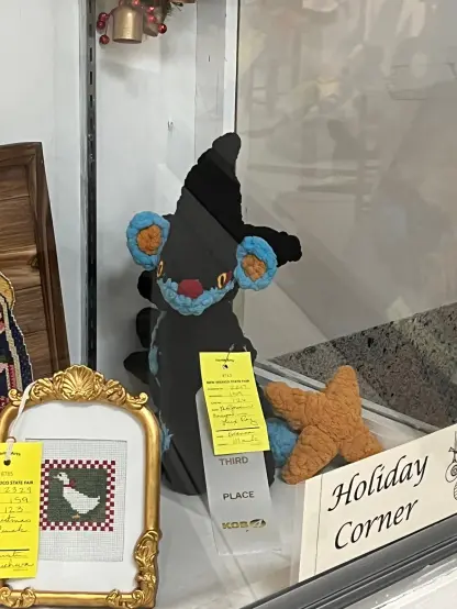 An image of a crochet Luxray in a display case.