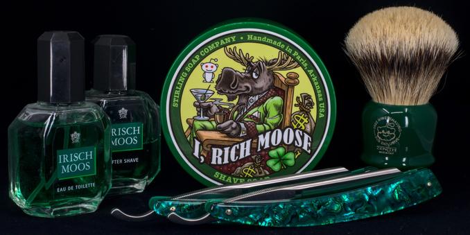 (Le Chat Mistral description)

This image shows a collection of shaving items arranged on a dark background. On the left, there are two green bottles of Irish Moos aftershave and eau de toilette. In the centre, there is a round tin of shaving soap labelled "I, Rich Moose," featuring a cartoon moose holding a drink. To the right of the tin, there is a green-handled shaving brush with light bristles. In front of the brush, there is a straight razor with a decorative, green, translucent handle. The items are vibrant and suggest a coordinated grooming set.