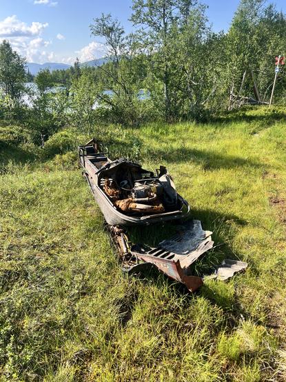 An abandoned, rusty snow mobile left on a meadow