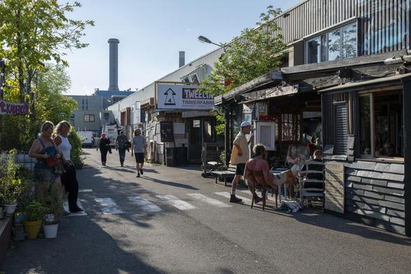 Een passage in het Werkspoorkwartier in Utrecht, waar mensen rondlopen of samen gezellig een drankje drinken in een barretje.