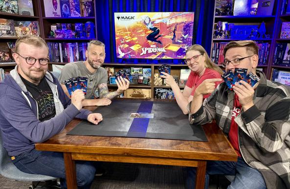 Graham, Adam, Cori, and Serge holding up packs of Magic:The Gathering cards featuring Spider-Man.