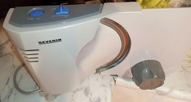 A universal cutter from Severin. The housing is aluminium with grey powdercoating. Only the dark gray plastic knobs and switch cover are plastic, along with blue switch at the top.