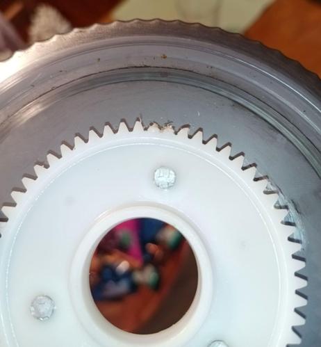 Inside of the rotary knife with a POM gear riveted to it. The center hole is for fixing the blade to the machine. The blade is not driven on its axle, but by a small gear driving this large gear instead, giving it plenty of power. Three of the teeth are stripped and frayed.