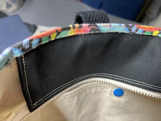 A close up view of the unzipped zipper over the main bag compartment.  A double line of stitching secures the zipper flap inside the top seam.