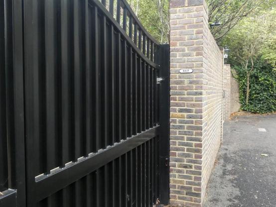 Black metal gates closed. On a wall beside the gate a small sign reads "Exit"