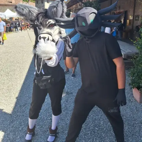 Photo of me in a the aforementioned partial fursuit of my axolotl fursona alongside another fursuiter (unknown) with a canine fursuit