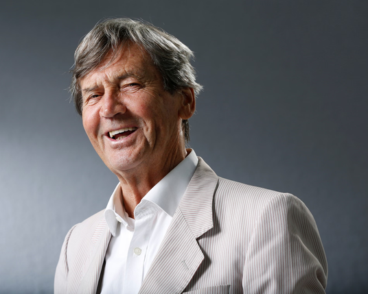The image features a middle-aged man with gray hair, smiling broadly. He is wearing a light-colored, pinstriped suit jacket over a white dress shirt, with the top button undone. The background is a plain, dark gray, providing a neutral backdrop that highlights the subject. The man's expression is cheerful, with his eyes slightly crinkled, suggesting a genuine smile. The lighting is soft and even, casting gentle shadows and enhancing the textures of his hair and clothing.

Provided by @altbot, generated privately and locally using Ovis2-8B

🌱