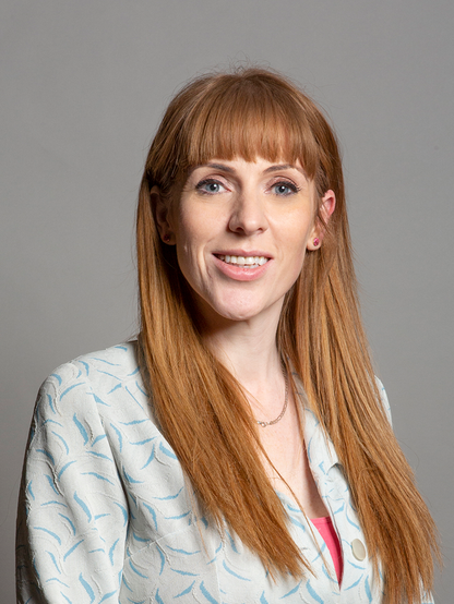 The image features a woman with long, straight, reddish-brown hair, wearing a light-colored blazer with a blue leaf pattern. She has blue eyes and is smiling, with her teeth visible. She is wearing a pink top underneath the blazer and a delicate necklace with a small pendant. Her hair is parted in the middle and falls straight down her shoulders. The background is a plain, neutral gray, providing a simple and unobtrusive backdrop.

Provided by @altbot, generated privately and locally using Ovis2-8B