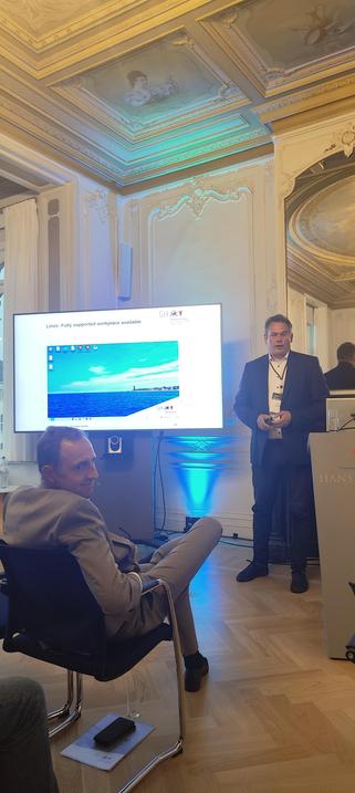 OSPO for Europe Event 3/9 in Brussels with a screenshot of KDE belonging to an undisclosed pilot OS project of Schleswig-Holstein.