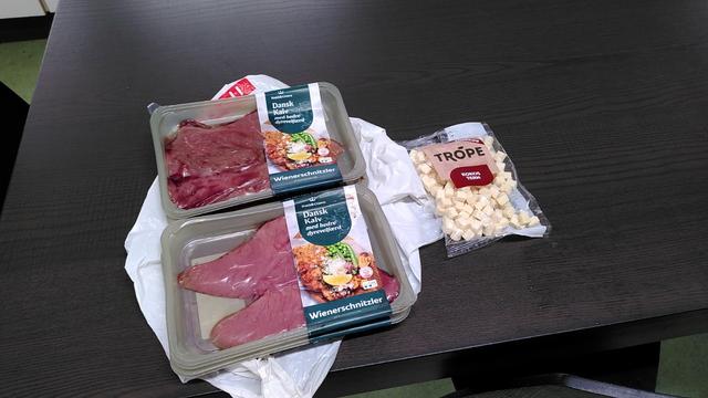 Picture showing four packages of beef Schnitzel meat stacked on top of a plastic shopping bag and a bag of dessicated coconut cubes