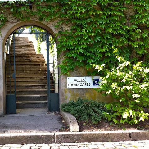 Photo carré. Sur la gauche, une porte dans un mur et un escalier extérieur derrière. À gauche, un mur recouvert de lierre.
En bas, un panneau "Accès handicapés" avec un logo fauteuil roulant.

En fait il y avait une flèche vers la droite mais elle est masquée par le lierre, et on pourrait croire que c'est l'escalier l'accès handicapés.
