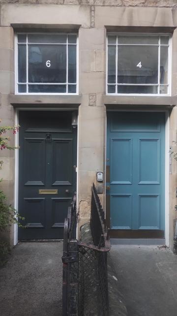 Two doors side by side, left one green, the right blue, with windows above them, one with the number 6, the right with the number 4