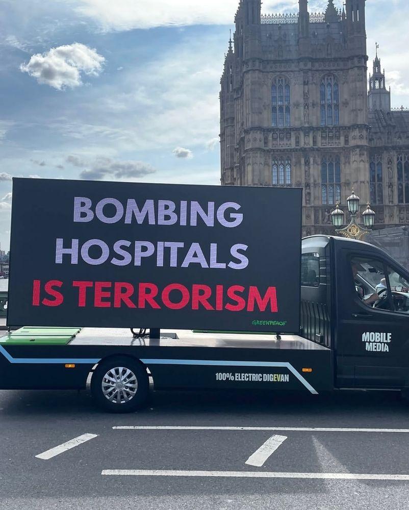 Greenpeace electric Truck showing the text  BOMBING HOSPITALS  IS TERRORISM in London