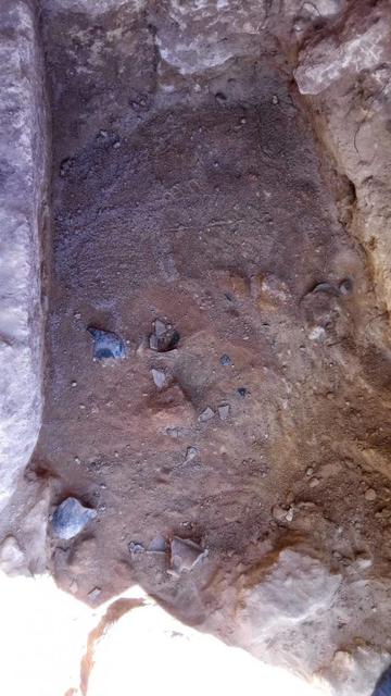 Immagine del fondo di una tomba etrusca inviolata, evidenziando la terra e le pietre sparse nel luogo dello scavo.