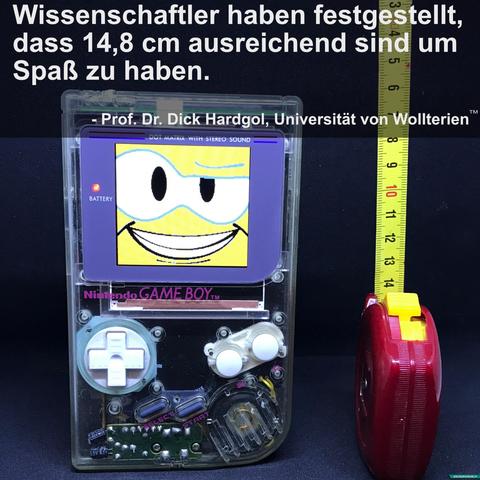 Das Bild zeigt einen transparenten Nintendo Game Boy (mit lilafarbenem Bildschirmrahmen) im Vordergrund. Auf dem Display ist ein grinsendes Cartoon-Gesicht zu sehen, das den Betrachter direkt anlächelt.
Rechts daneben steht ein Maßband, das die Höhe des Game Boys misst – etwa 14,8 cm.
Oben im Bild steht ein humorvoller Spruch in weißer Schrift:
„Wissenschaftler haben festgestellt, dass 14,8 cm ausreichend sind um Spaß zu haben.“
Darunter folgt ein angebliches Zitat:
„– Prof. Dr. Dick Hardgol, Universität von Wollterien™“
Das Ganze ist offensichtlich satirisch und witzig gemeint, spielt mit einem doppeldeutigen Gag über die Größe von 14,8 cm – gemeint ist aber der Game Boy, der „ausreichend“ ist, um Spaß zu haben.