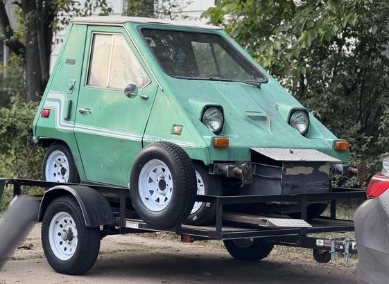 A lime green car that looks like a cheese wedge. It’s a two seater and is basically a street legal golf cart turned car.