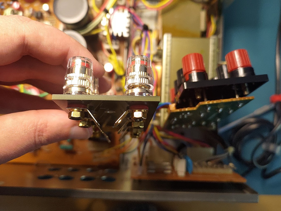 The original speaker terminals of a Luxman LV-103 amplifier next to the replacement mentioned in the post. The new set is a simpler PCB setup, and the terminals are full-size binding posts with banana-plug (4mm) holes. Their plastic coverings are transparent plastic, whereas the old set had opaque red/black coverings.