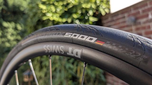 Nahaufnahme eines Rennradreifens auf Felge. Auf der Felge steht "DT SWISS" auf dem Reifen "GP 5000".