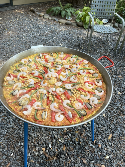 Before-a very large paella pan, golden rice, 50 scattered prawns, red peppers,clams, garbanzo beans