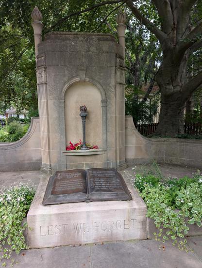 Memorial to Lieutenant Colonel John McRae at his birthplace in Guelph, Ontario. Torch in the background with an open book in the foreground open to "In Flanders Fields." The monument has "Lest We Forget" inscribed on its base.