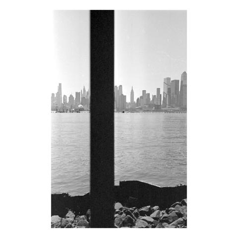Behind a single black bar in the foreground is an amazing view of mid-town manhattan, with the iconic Empire State Building prominent in the skyline.