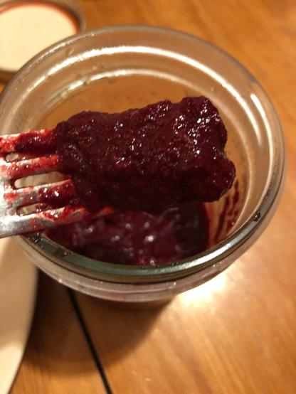 a spoonful of jam made from rhubarb and aronia berry that is a reddish-purple and creamy consistency