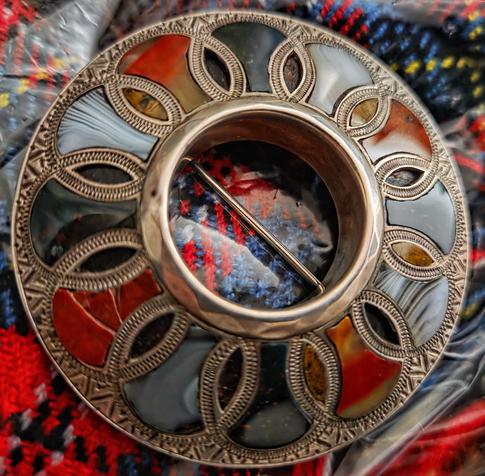 The brooch is round and the silver mount of overlapping circles creates large and small agate shapes. 

The silver mount is engraved with scroll designs. One of the outer red jasper stones is chipped and cracked – sadly most of the smaller shapes are empty – although the only way you can tell is to look at the depth of the mount, as the dark backing stone is showing through, and looks like a regular agate mount.