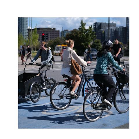 Drei Radfahrende

Einer in Jogger und weitem Pulli mit Kopfhörern und Mütze auf Lastenrad, eine chic in Beigetönen und die Dritte in Outdoorkleidung.