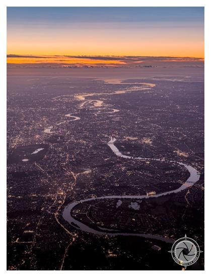 An aerial view of London at sunrise, the Thames reflecting the early morning sunlight snakes through the city on its way to the Thames estuary and the English Channel in the distance.