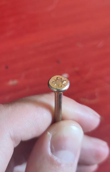 Closeup to the head of the philips screw. The inside of the head is completely filled in with a molten metal, apparently the same as the rest of the screw is made of.